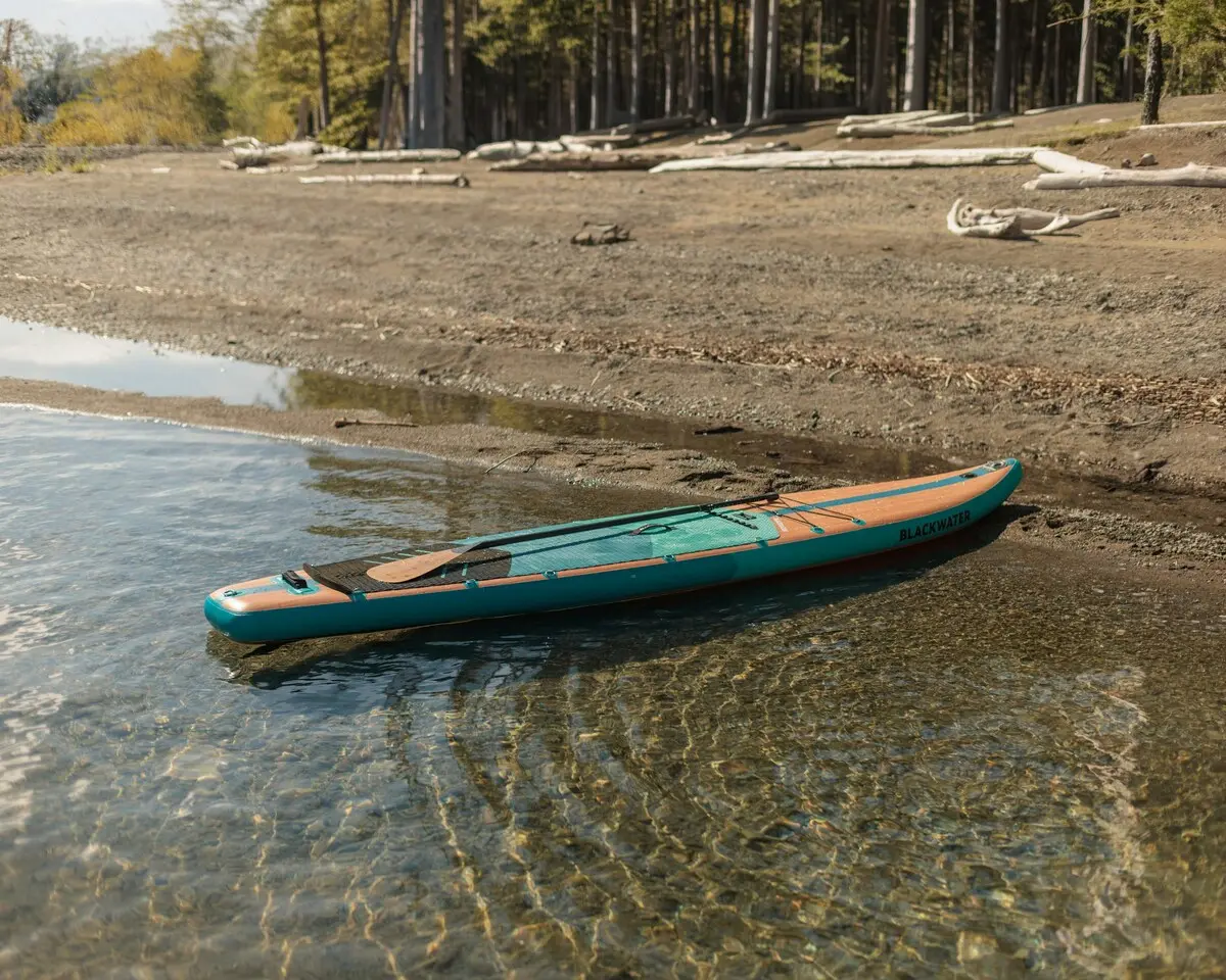 一塊立槳板停在清澈的湖岸邊